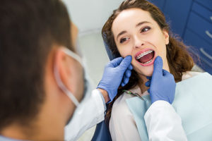 A dentist checks a woman's dental braces in TX