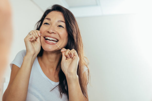how to prevent tooth decay (1) A woman flosses and wonders how to prevent tooth decay
