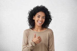 a woman gives a thumbs up after getting fluoride treatments and fluoride supplements in webster tx