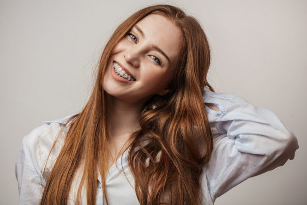 how long will i need to wear braces a woman smiles as she thinks about orthodontics and wonders how long will i need to wear braces