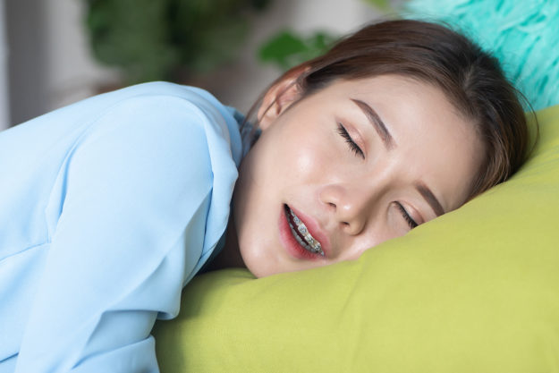 one woman sleeping on bed at home; asian woman alone sleeping for concept of rest at home, resting, social distancing, physical distancing, stay home, self isolation, new normal woman sleeping with teeth grinding problems