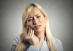 woman struggles with the the pain caused by impacted teeth