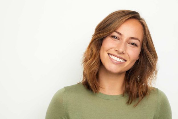 a woman smiles as she thinks about how oral health and mental health are connected